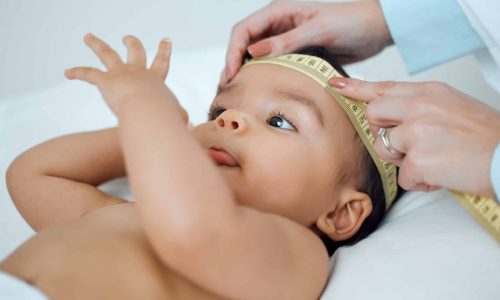 Shot of a paediatrician measuring a babys head in a clinic.